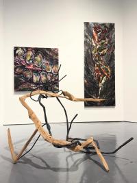 A wooden artwork with pieces of metal laced around the wood