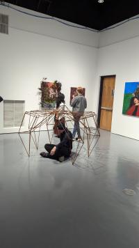 Picture of 3d artwork and of people looking at paintings