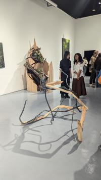A 3d artwork made of wood and metal with students chatting in the background