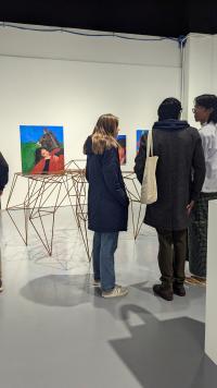 People looking at a 3d artwork with paintings hanging on the walls in front of them