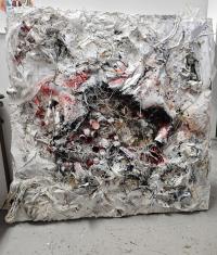 White and red artwork with tree branches and debris stuck to a canvas